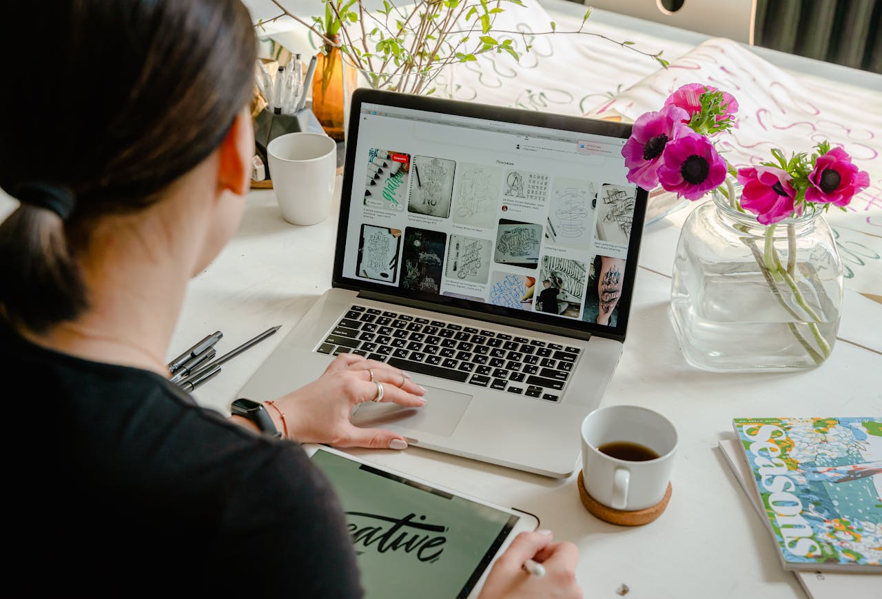 Crafting Captivating Headlines: Your awesome post title goes here Woman in a creative workspace using a laptop and tablet for calligraphy. Artistic and tech-driven environment.